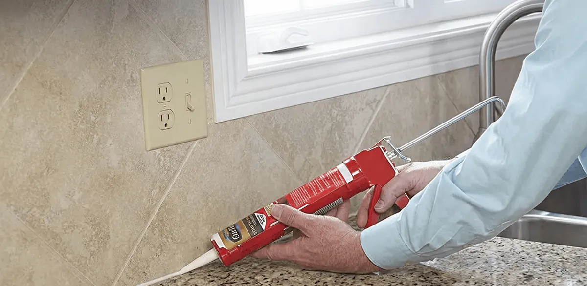 Handyman applying caulk along a kitchen backsplash and countertop seam in New Orleans, LA