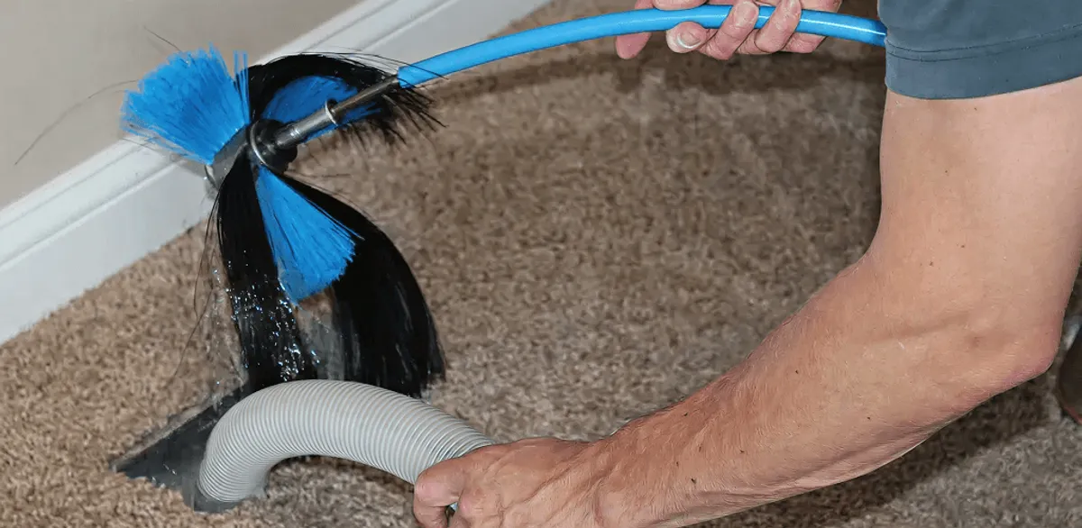 Dryer vent cleaning technician brushing lint from a vent line in New Orleans, LA