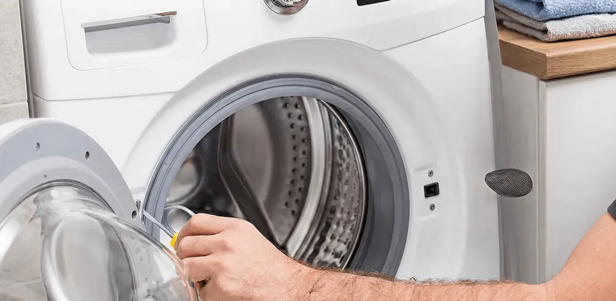 Handyman repairing a front-load washing machine and inspecting the drum in New Orleans, LA