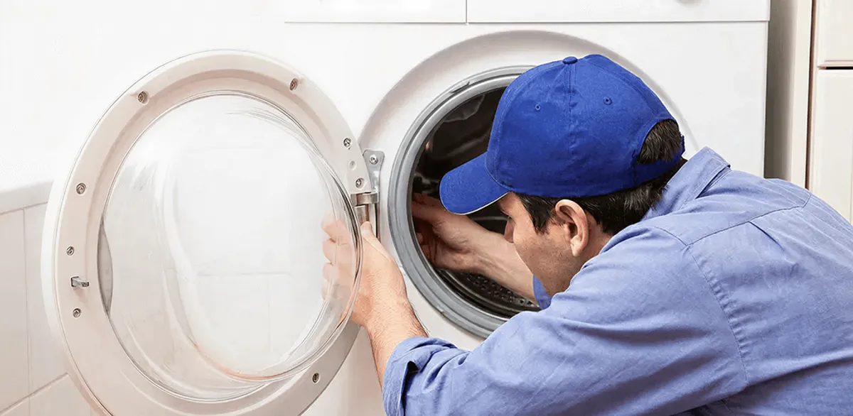 Washing machine repair handyman inspecting a front-load washer drum in New Orleans, LA